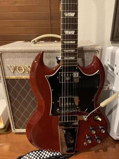 an electric guitar sitting on top of a wooden table next to a speaker and amp