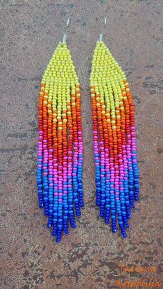 two pairs of multicolored beads are hanging from silver hooks on a brown surface