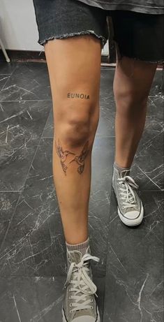 the legs and ankles of a person with tattoos on them, both wearing white sneakers