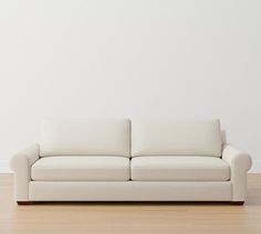 a white couch sitting on top of a hard wood floor next to a white wall