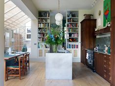 an open kitchen and dining room with wooden flooring, bookshelves and cabinets