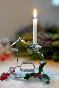 a candle that is sitting in the snow next to a sleigh and holly