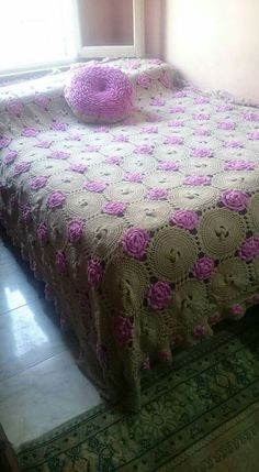 a bed with pink and white crocheted bedspread on top of it