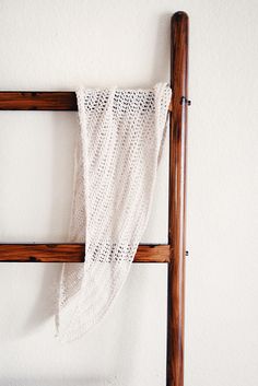 an old wooden ladder with a white crocheted blanket hanging from it's side