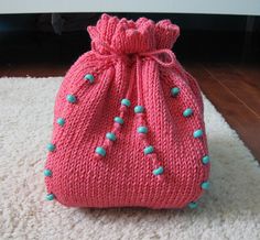 a pink knitted bag sitting on top of a white rug