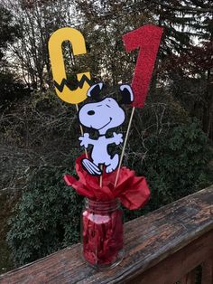 a mason jar filled with candy sitting on top of a wooden fence next to a number sign