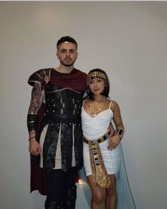 a man and woman dressed up in roman garb, standing next to each other