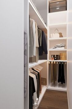 an open closet with clothes hanging on shelves