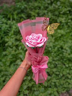 a person holding a pink flower with a butterfly on it