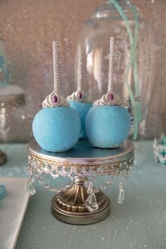 three blue donuts sitting on top of a cake stand