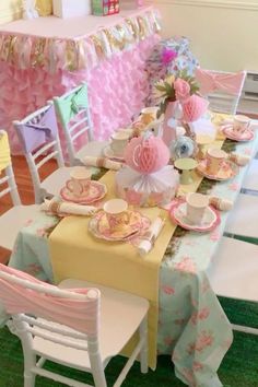 a table set up for a tea party with pink and yellow decorations on the tables