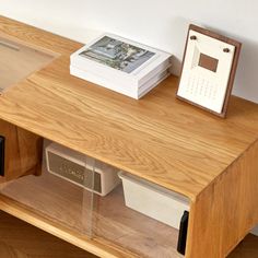 a wooden table with a phone and other items sitting on it's shelf next to a white wall