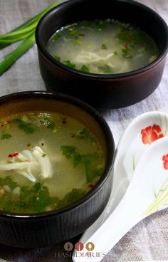 two black bowls filled with soup on top of a table