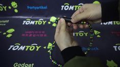 a person holding a cell phone in front of a sign that says tomtoy