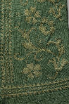 an old green and gold cloth with flowers on it