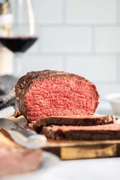 a piece of meat sitting on top of a cutting board next to a glass of wine