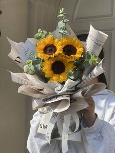 a woman is holding a bouquet of sunflowers with ribbons around her neck and head