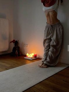 a woman standing on top of a rug next to candles