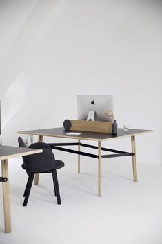 an apple computer sitting on top of a wooden desk next to a chair and table