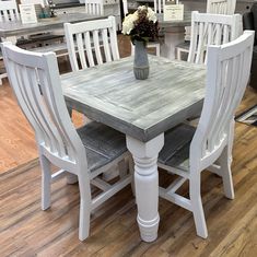 a kitchen table with four chairs and a vase on the table in front of it