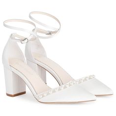 a pair of white high heeled shoes with pearls on the toes and ankle straps