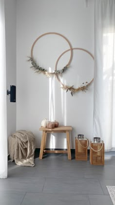 a white room with two circular wall hangings on the wall and a wooden bench in front of it