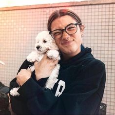 a woman holding a small white dog in her arms