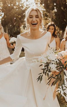 the bride is laughing as she walks down the aisle with her bridesmaids in white dresses