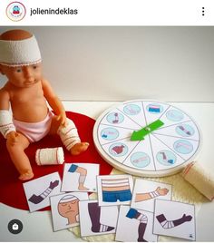 a doll sitting on top of a red table next to some cards and an object