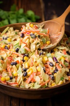 a salad in a bowl with a wooden spoon