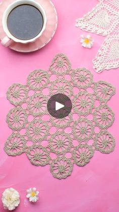 a cup of coffee and doily on a pink surface