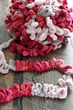 two crocheted pieces of yarn sitting on top of a wooden table