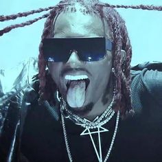 a man with dreadlocks sticking his tongue out and wearing sunglasses in front of him