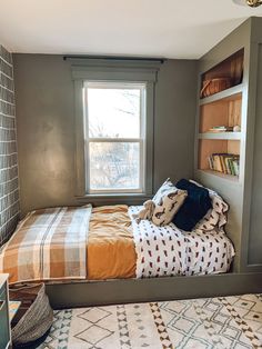 a small bedroom with a bed, window and rug on the floor in front of it