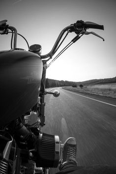 black and white photograph of motorcycle driving down the road