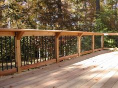 a wooden deck with metal railings and trees in the background