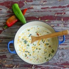 a pot filled with soup sitting on top of a wooden table next to two peppers