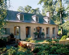 the house is surrounded by greenery and trees, with two large windows on each side