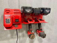 a red work bench with drillers and tools hanging from it's hooks on the wall