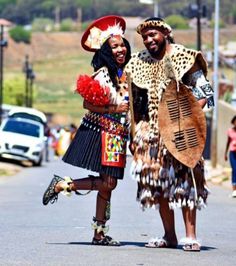 two people dressed in costumes standing on the side of a road next to each other