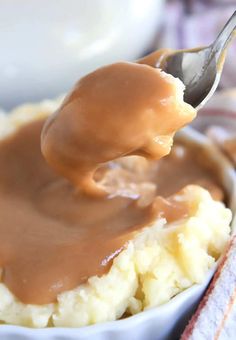 a spoon full of gravy on top of mashed potatoes