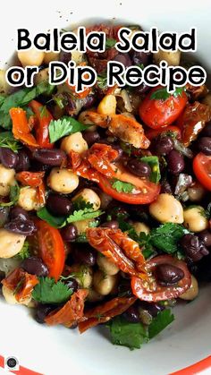 a white bowl filled with black olives, tomatoes and other vegetables on top of a table