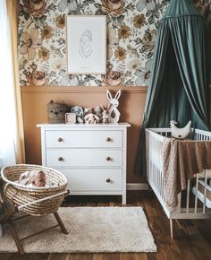 a baby's room with floral wallpaper and white furniture