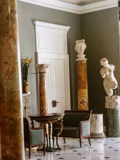 a room filled with furniture and statues on the wall next to a doorway that leads to another room