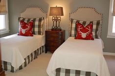 two twin beds with white and red bedding in a gray walled room, one has a deer head on the wall