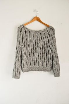 a sweater hanging on a hanger with a white wall in the background and an orange string attached to it