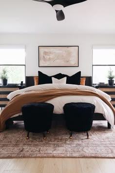 a large bed with two black chairs in front of it