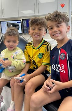 three young children sitting on a dental chair