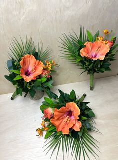 three orange flowers and green leaves are arranged on a white countertop with palm fronds