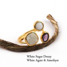 "Genuine Druzy Amethyst & Agate Gemstone Ring, Gold Plated Three Stone Adjustable Ring, Collet Set Wholesale Price Dainty Ring For Her (1760) Product Specifications : Gemstone Name : White Sugar Druzy/ Purple Amethyst/ White Agate Stone Shape : Round, Cushion, Oval Stone Color : White/ Purple Stone Size : 8 MM/ 6 MM/ 5X7 MM Approx Ring Size : Adjustable Material : Brass Plating : Gold Plated  Making : Handmade P. Code : 1760 Quantity : Drop Dwon This Rings are made by Brass material with gemstone. It's looking very beautiful with gold plating. You can Be wear it any party, Vacation, Travel etc. You can carry it on you casually. We have lots of designer fashion jewelry. We are manufacturer, wholesaler and exporter of gemstones and handmade jewelry. We always try fulfilled our customers requ Adjustable Multi-stone Moonstone Ring Gift, Adjustable White Gemstone Stackable Rings, Adjustable Stackable Rings With Gemstone Accents, Adjustable White Crystal Ring With Birthstone, Adjustable Agate Crystal Ring With Gemstone, Adjustable Gemstone Accented Rings As Gifts, Adjustable White Rings With Natural Stones, Adjustable Amethyst Ring With Gemstone Accents, Adjustable Rings With Gemstone Accents For Gift